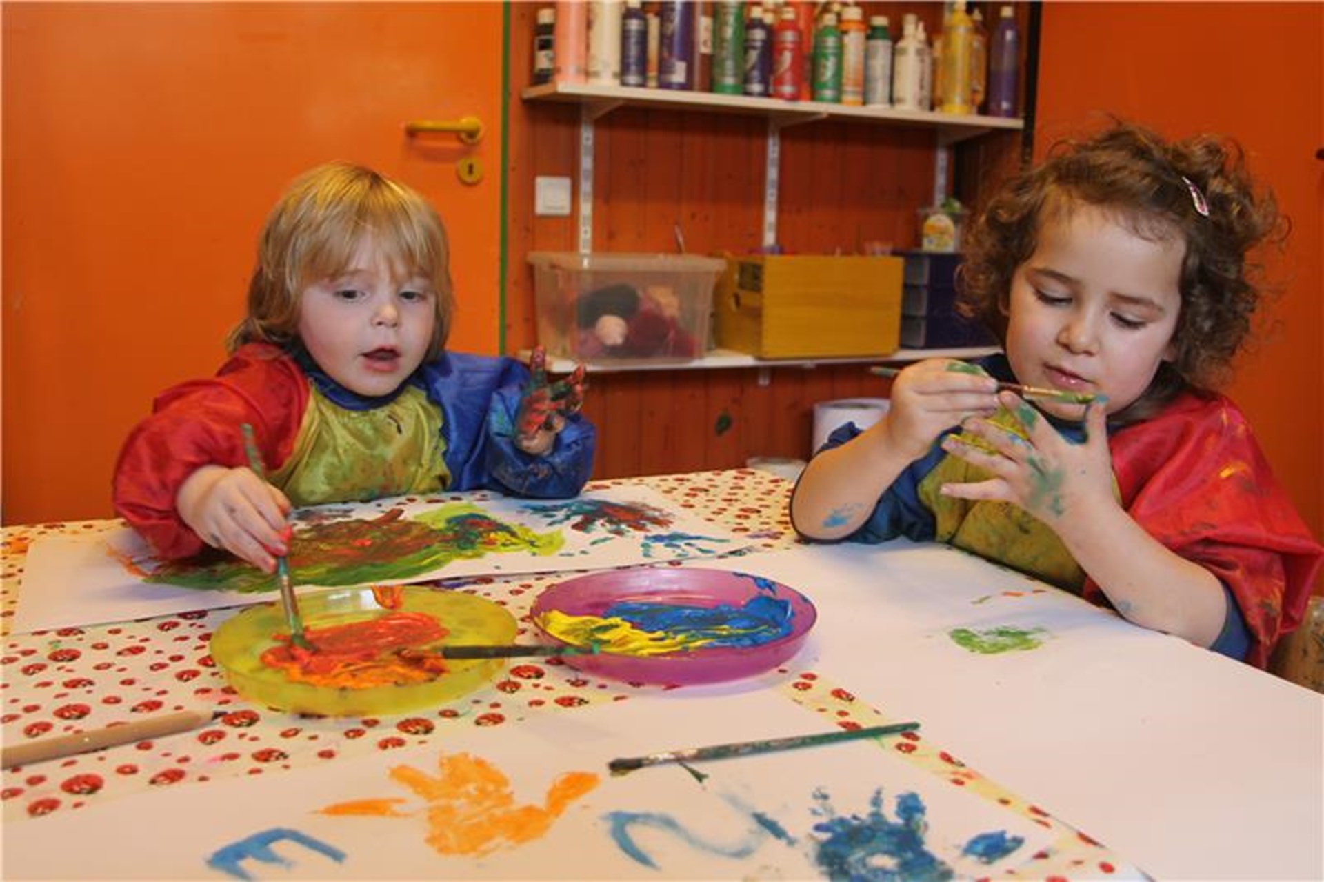 Zwei Kinder sitzen an einem Tisch und malen mit Abtönfarbe