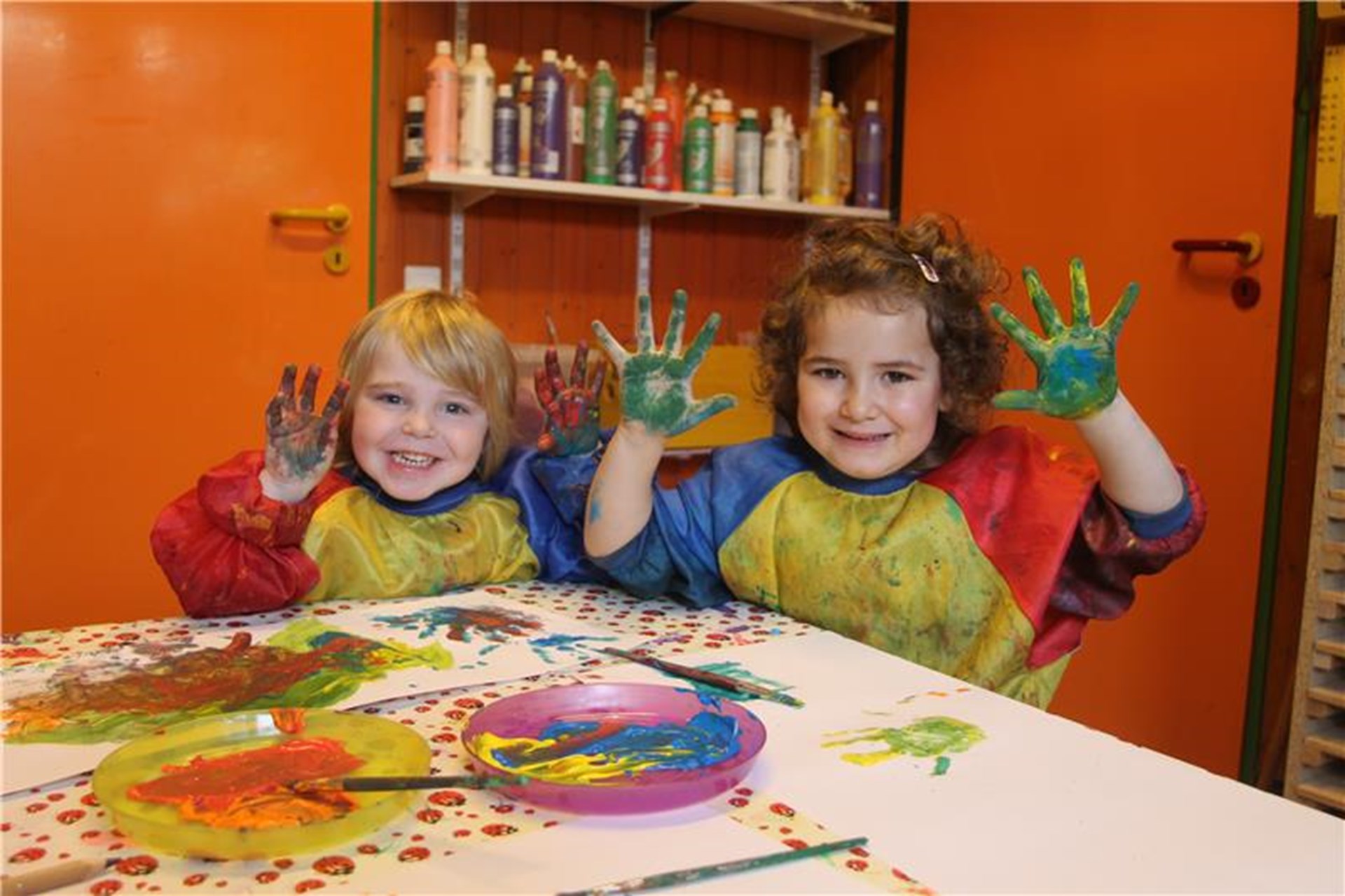 Zwei Kinder sitzen an einem Tisch und malen mit Abtönfarbe