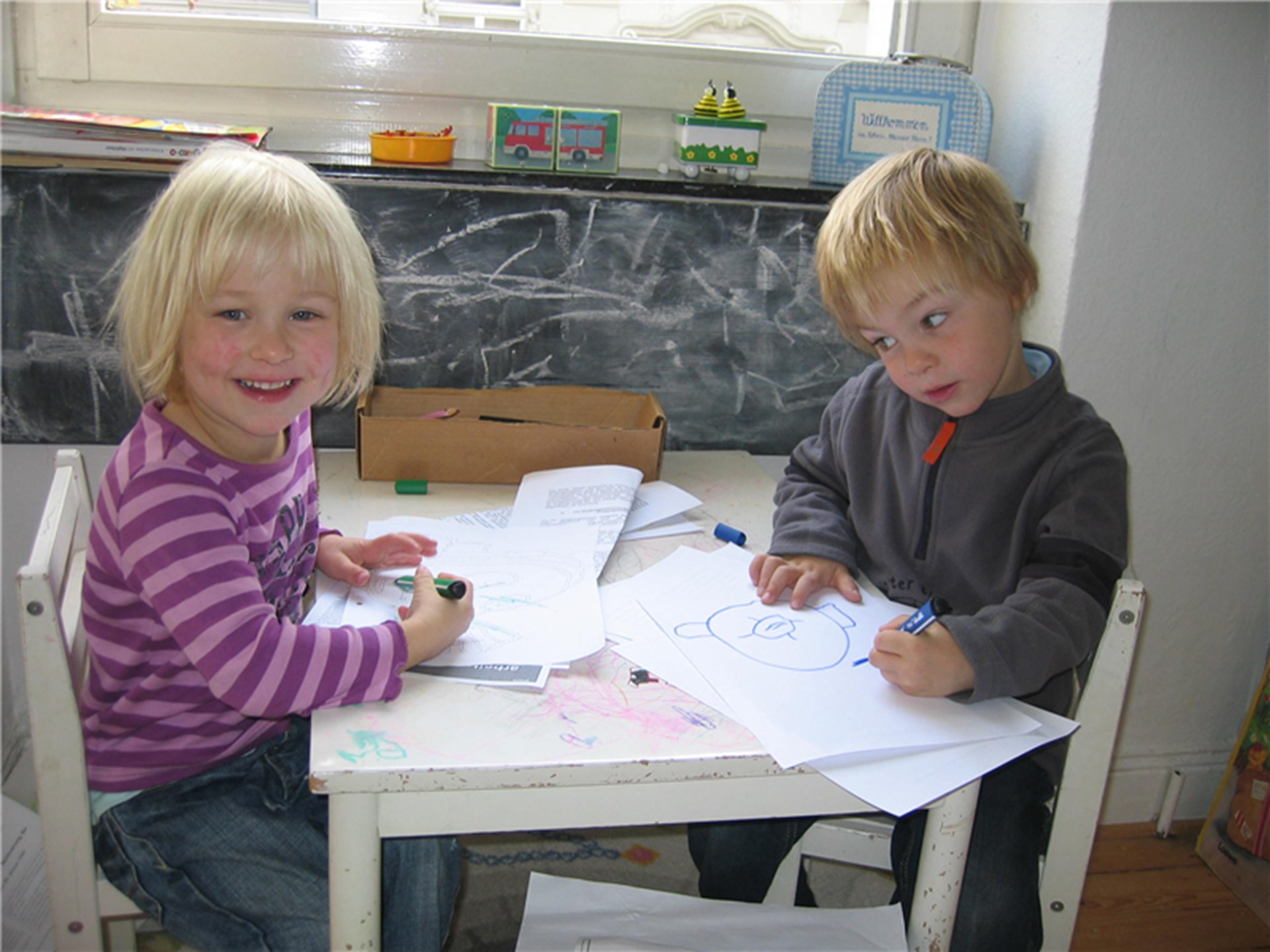 Zwei Kinder sitzen an einem kleinen Tisch und spielen