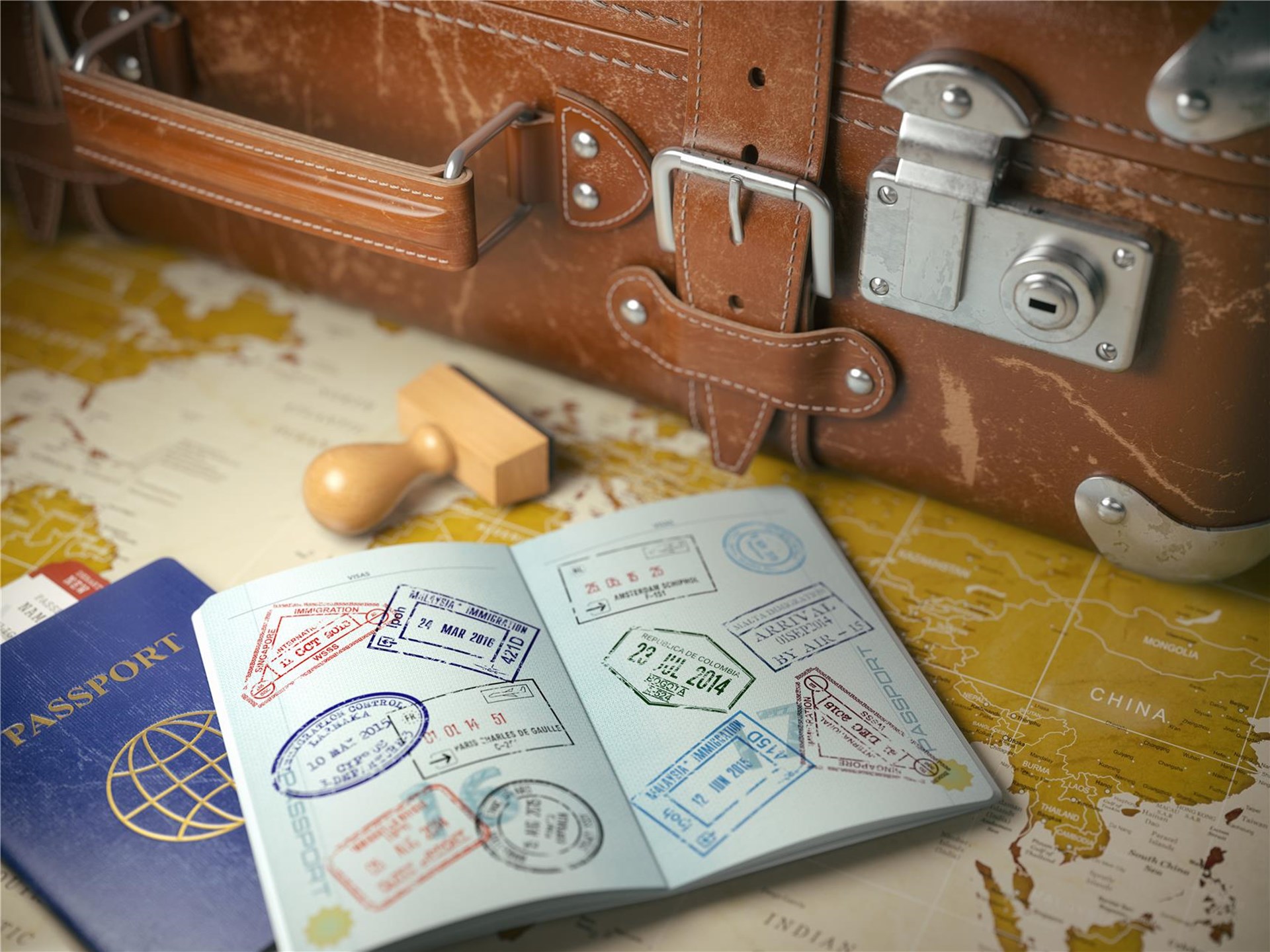 Ein Koffer, ein Stempel und zwei Pässe liegen auf einer Landkarte