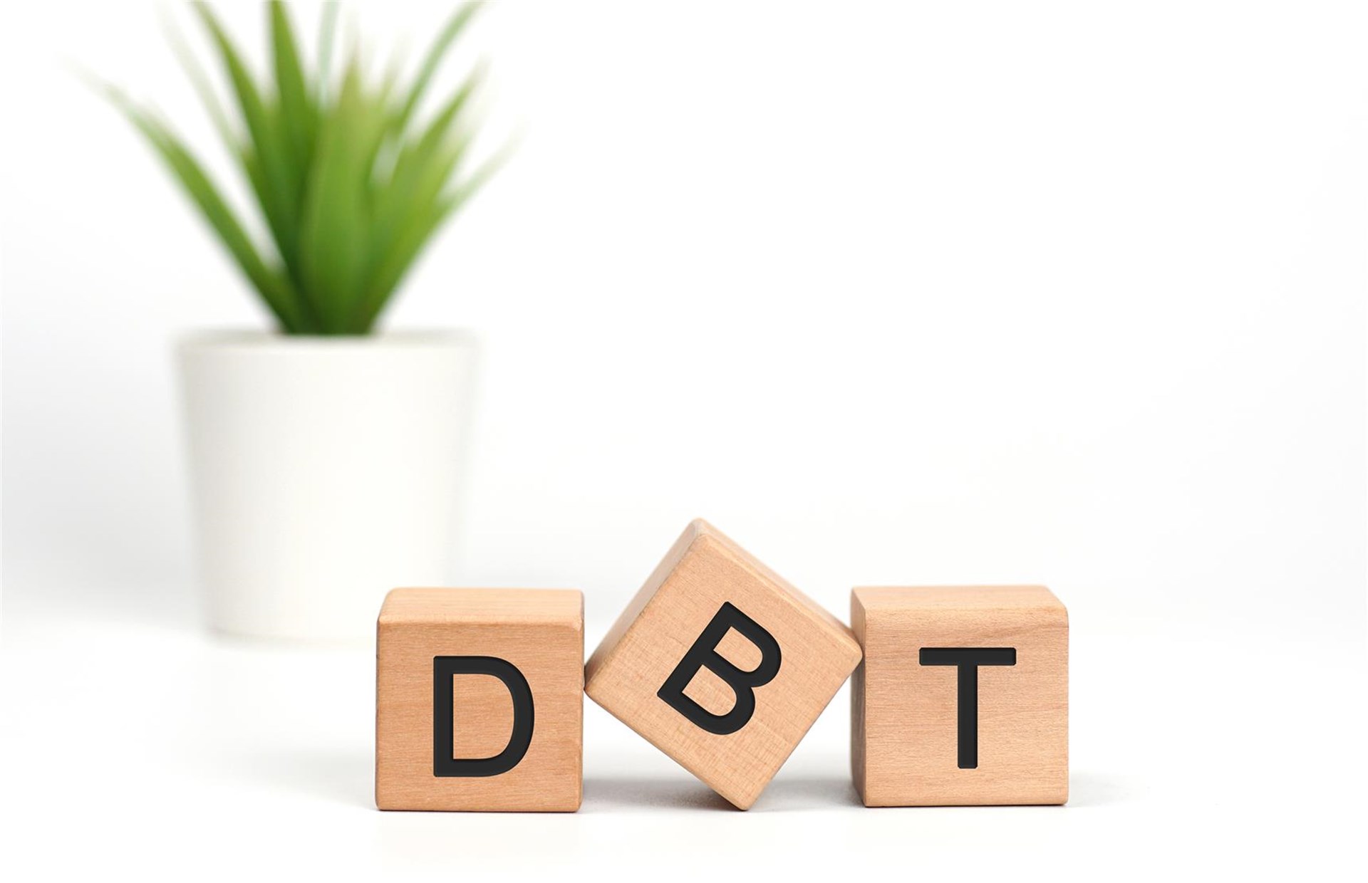 Drei Holzwürfel auf denen jeweils ein Buchstabe gedruckt ist, es sind die Buchstaben D, B, T