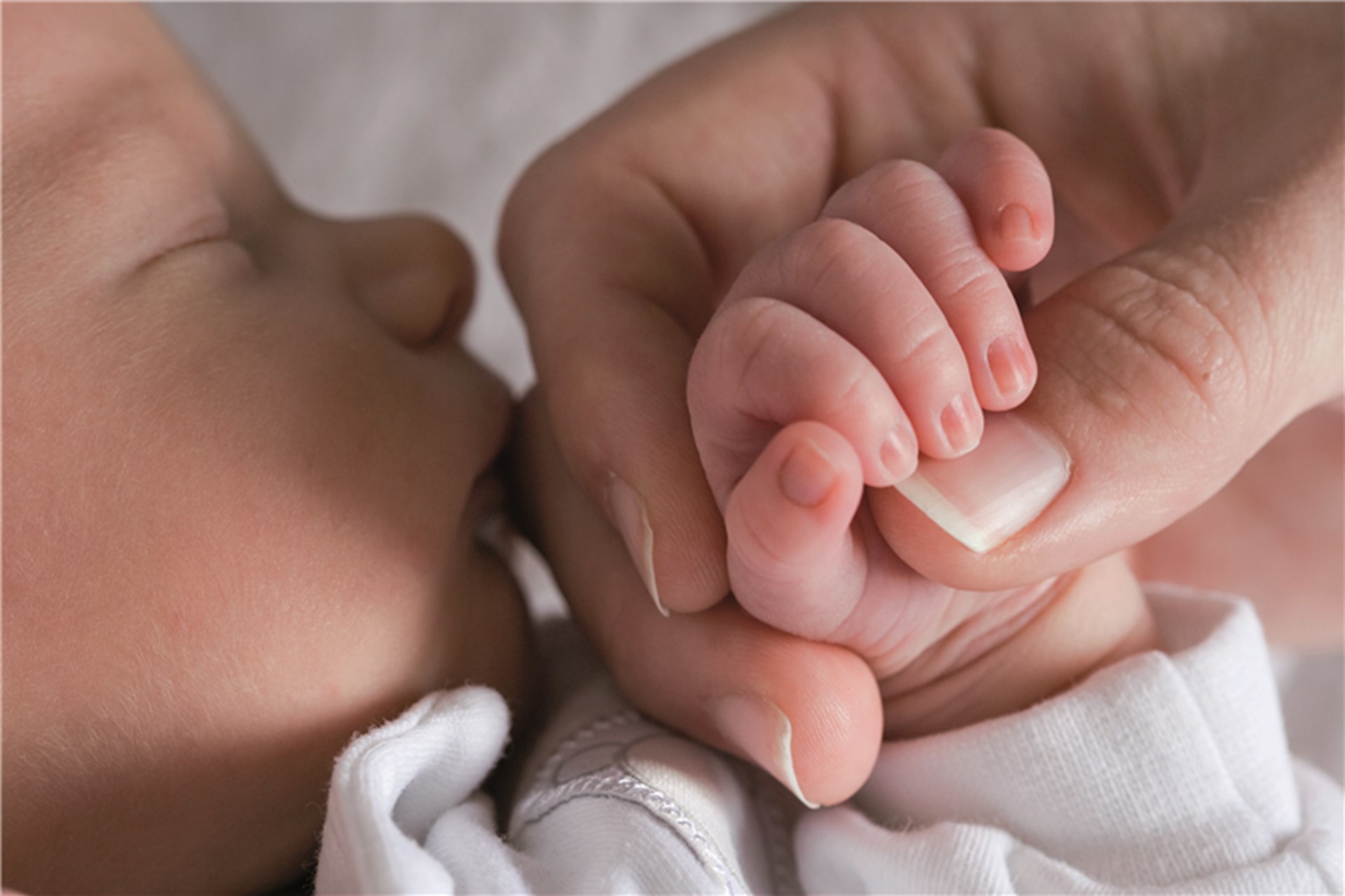 Die Hand einer Frau hält die Hand eines schlafenden Babys