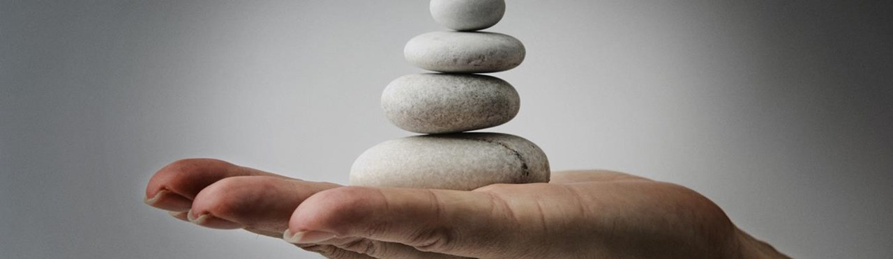 Eine Hand hält einen Turm aus Steinen