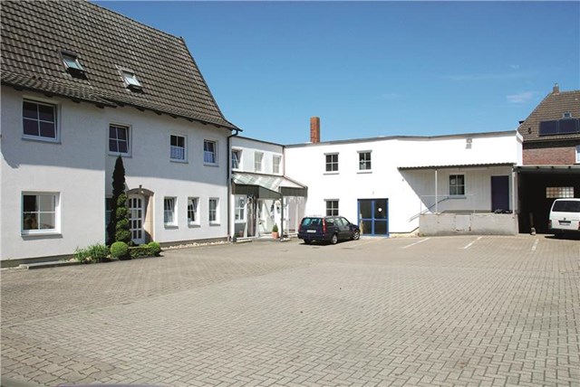 Großer Hof mit Gebäuden, Eingangsbereich und zwei Autos