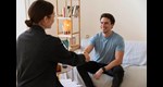 Ein Mann und eine Frau sitzen sich in einem Wohnzimmer gegenüber und geben sich die Hand.