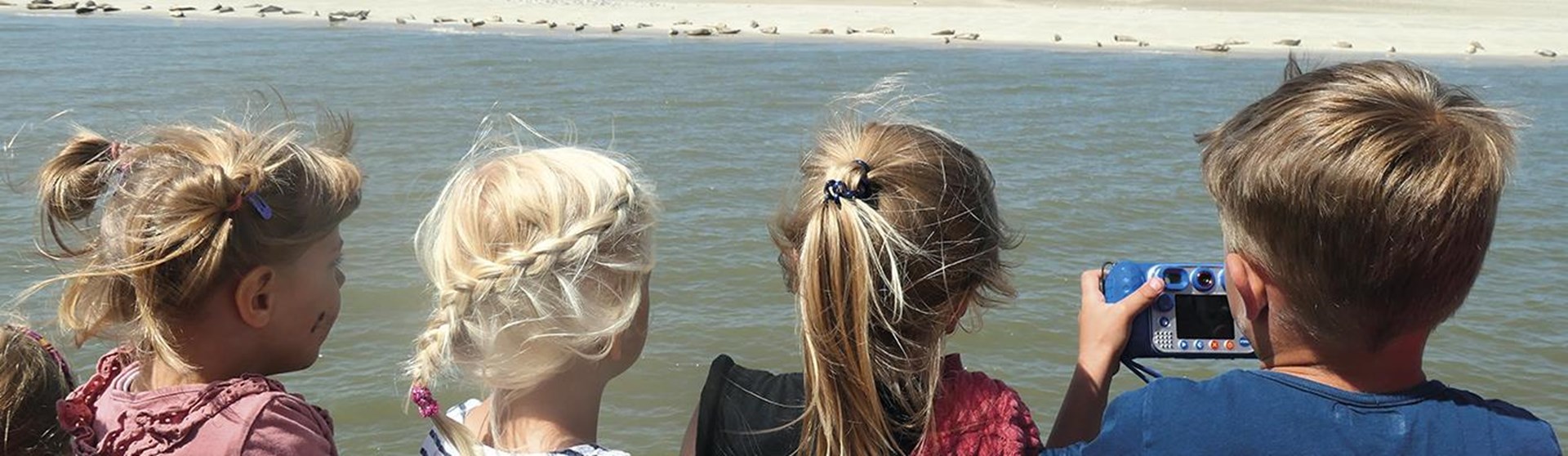 Vier Kinder von hinten abgebildet gucken auf die Nordsee