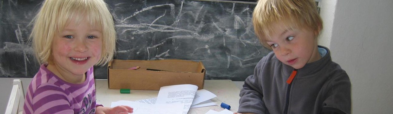 Zwei Kinder sitzen am Tisch und spielen