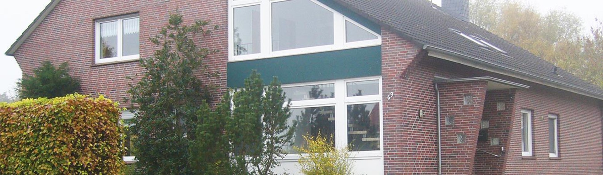 Gebäude mit Baum und Hecke davor