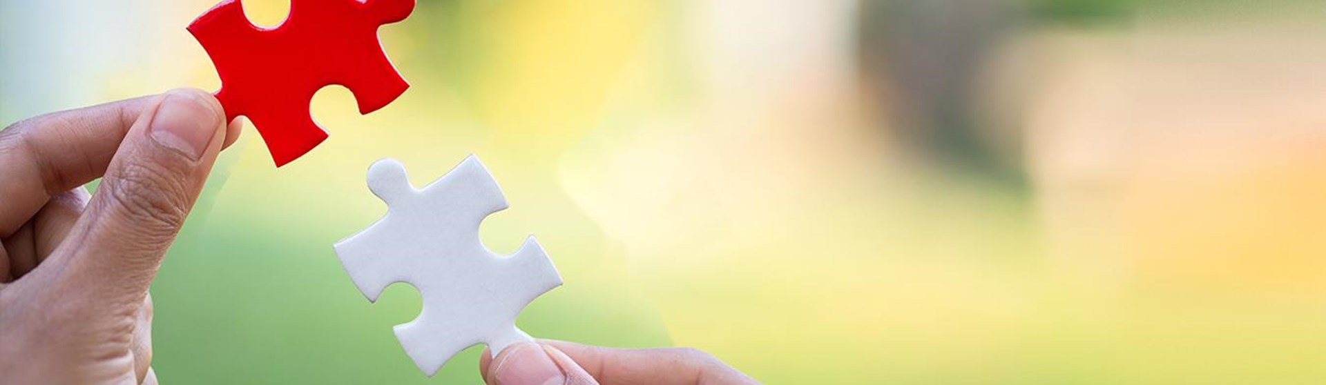 Zwei Hände halten jeweils ein Puzzleteil